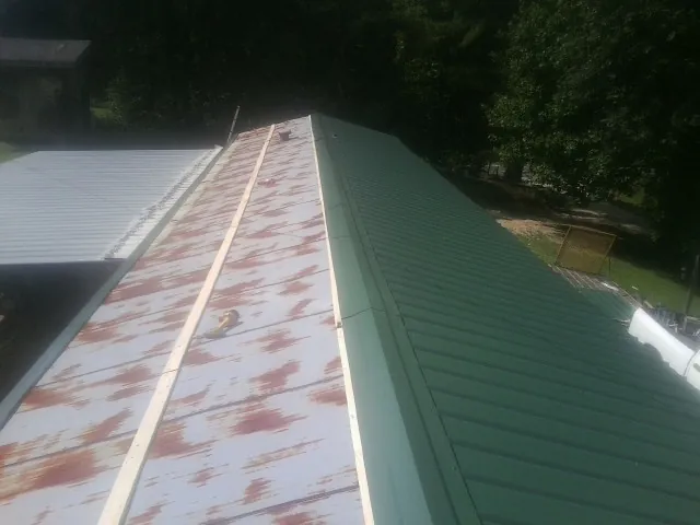 Old rusted panels beside newly installed green metal roofing — Wind Damage Roof Repair by Roofing Brothers in Sherman