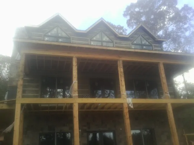Dormers and porch framing on a large log home under construction — Roof Coating work by our crew in Sherman